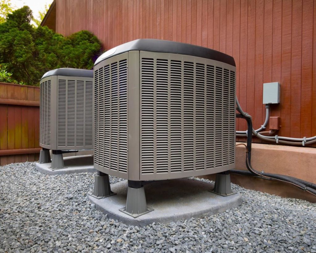 An AC unit displayed beside a wooded fence