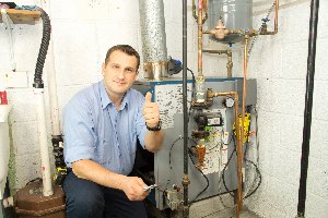 An HVAC technician giving a thumbs up after working on a furnace